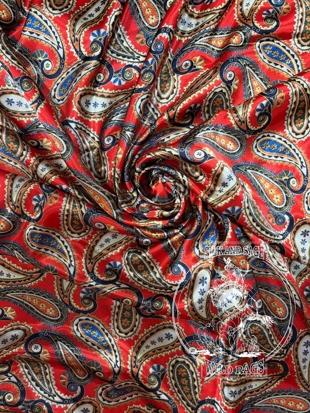 Rich red paisley with hints of navy, cream, greens, and gold. Med weight charmeuse satin fabric.