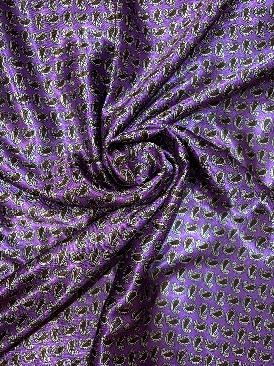 Purple back ground with small paisley print. Med weight charmeuse satin fabric.