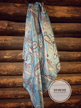 Load image into Gallery viewer, Light sky blue with white, tan, and a hint of pinkish mauve tone paisley on a silky charmeuse.
