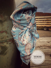 Load image into Gallery viewer, Light sky blue with white, tan, and a hint of pinkish mauve tone paisley on a silky charmeuse.
