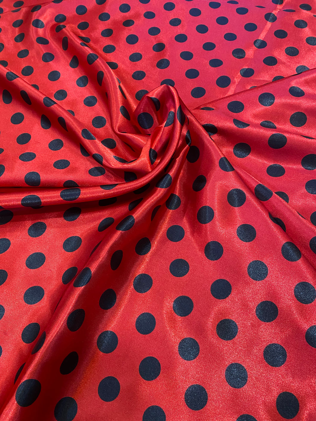 Bright red with black polka dots on a soft, satin charmeuse fabric.